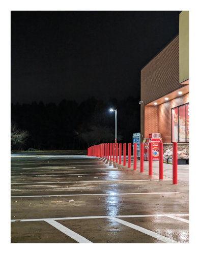 night. angled view of parking spaces and red bollards in front of a circle k. no people or cars in the picture.