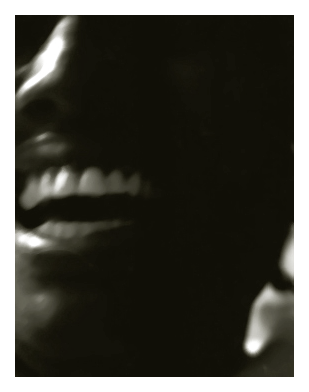 extreme close-up of a Black woman in her late 20s laughing.